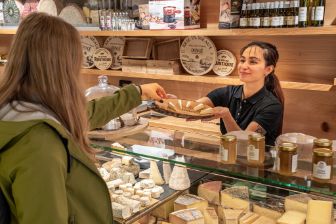 Die Mitarbeiterin vom Chaesbueb Zytglogge überreicht einer Kundin ein Stück Käse zum Probieren. 