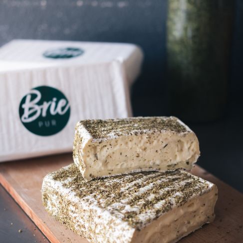 Kräuterbrie mit Kräutern im Teig und auf der Oberfläche.